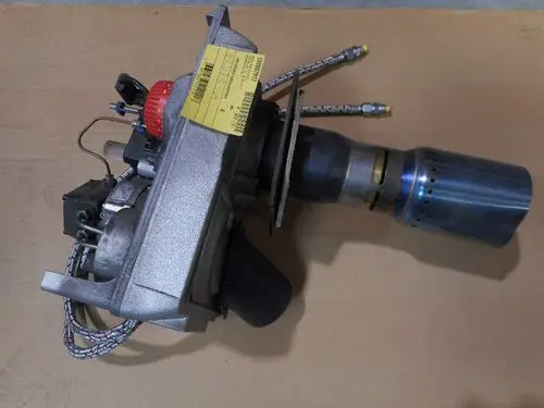 Remeha Heizgerät mit mehreren Komponenten, darunter ein Motor, Rohrleitungen und eine Auspufföffnung aus Metall, auf einer flachen Unterlage platziert.
